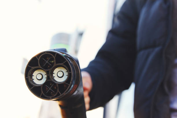 Man holding electric car charger plug type CHAdeMO at charging station with sunflare | Imagem de 1 carregador elétrico tipo CHAdeMO | Imagem de 1 carregador elétrico tipo CHAdeMO. Fonte: iStock